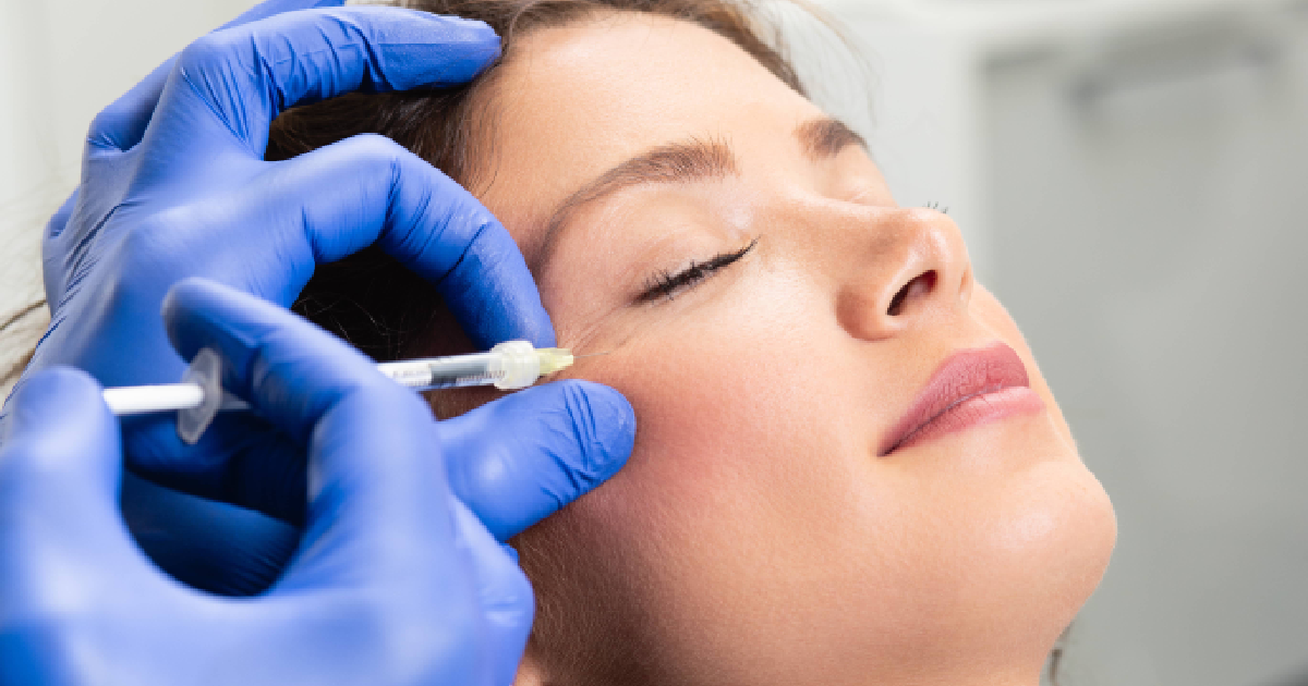 Woman receiving a dermal filler injection in the cheek area from a medical professional wearing blue gloves in Brooklyn, NY