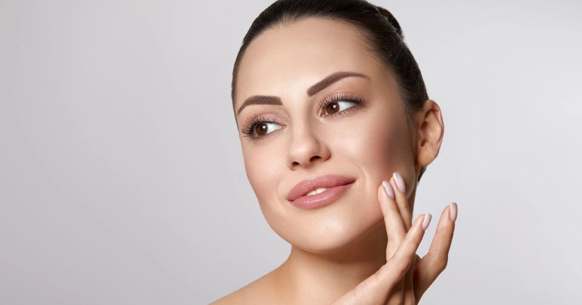 Woman showing smooth, youthful skin after Non-Surgical Facelift in Brooklyn, NY, touching her face and showing rejuvenated results.